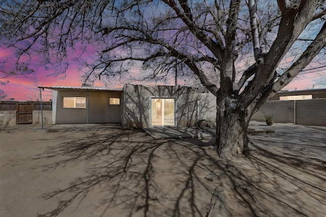 back of house featuring fence and stucco siding