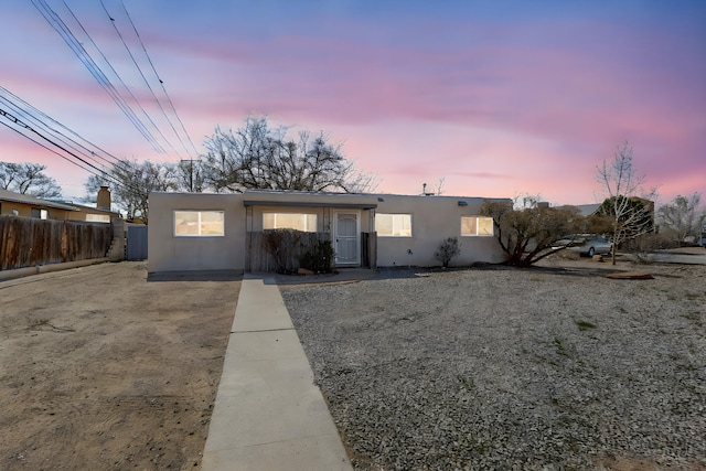 view of front facade featuring stucco siding and fence