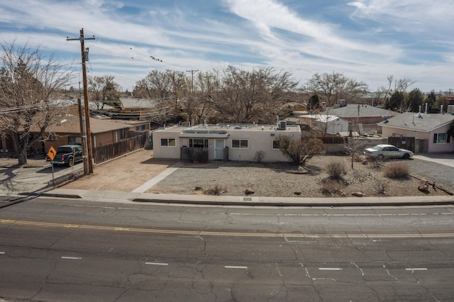 view of front of house featuring driveway, fence, a residential view, and stucco siding