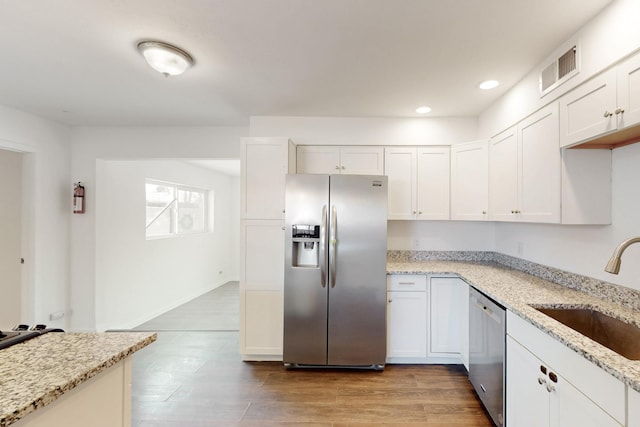 kitchen featuring appliances with stainless steel finishes, white cabinetry, a sink, and wood finished floors