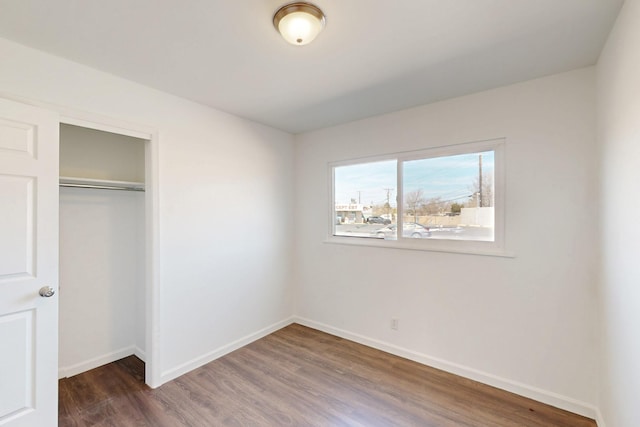 unfurnished bedroom with a closet, baseboards, and wood finished floors