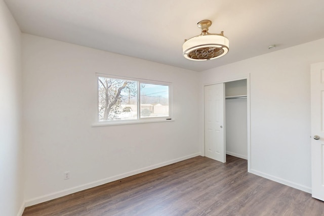 unfurnished bedroom with a closet, baseboards, and wood finished floors