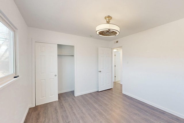 unfurnished bedroom featuring a closet, baseboards, and wood finished floors