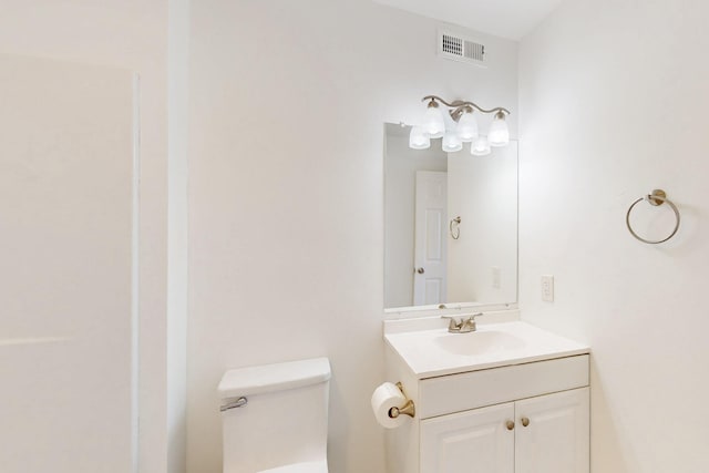 half bath with toilet, vanity, and visible vents