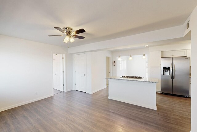 kitchen featuring light stone countertops, baseboards, appliances with stainless steel finishes, and dark wood-type flooring