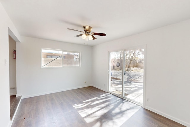 spare room featuring a ceiling fan, a healthy amount of sunlight, baseboards, and wood finished floors