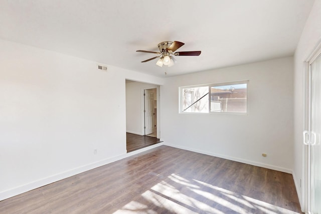 empty room with a ceiling fan, visible vents, baseboards, and wood finished floors