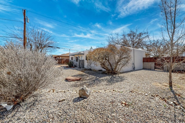 rear view of house with fence and stucco siding