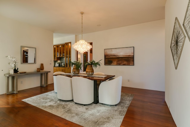 dining area with wood finished floors and an inviting chandelier