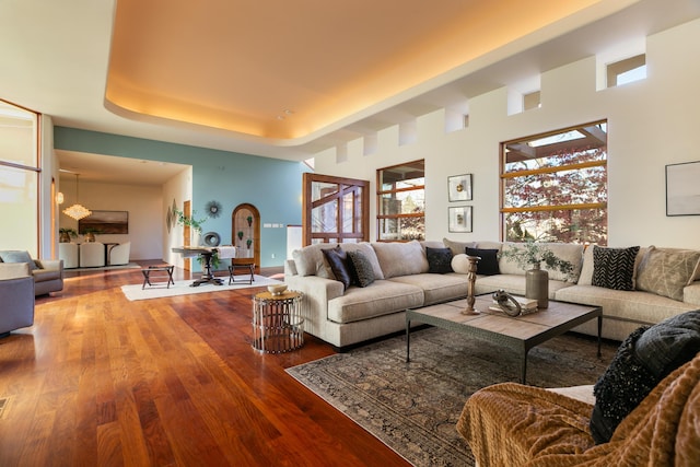 living room with a raised ceiling and wood finished floors