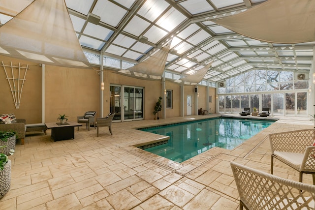 indoor pool featuring outdoor lounge area, a patio area, and a lanai