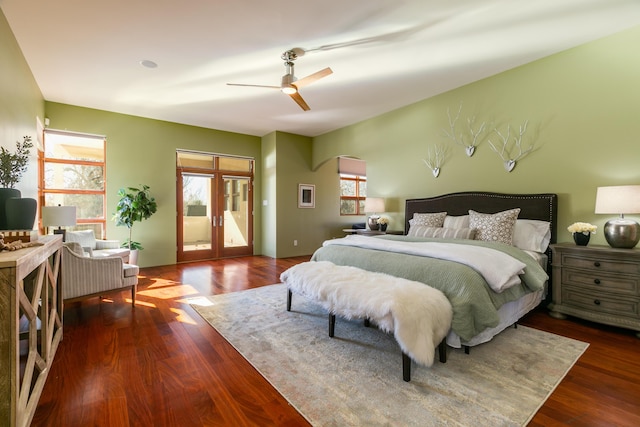 bedroom with access to exterior, multiple windows, arched walkways, and dark wood-type flooring