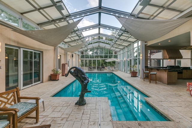 pool with a patio area, glass enclosure, area for grilling, and a grill