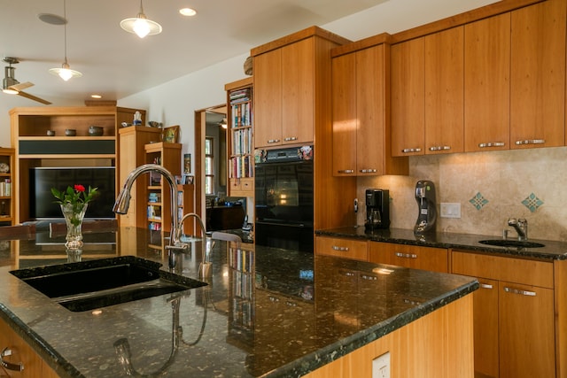 kitchen with brown cabinetry, a large island with sink, a sink, and backsplash