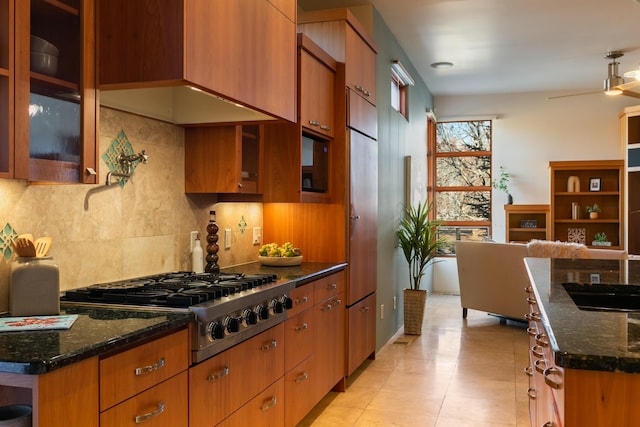 kitchen with tasteful backsplash, dark stone counters, brown cabinets, and stainless steel gas stovetop