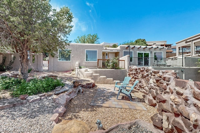 rear view of property with a pergola, a patio area, fence, and stucco siding