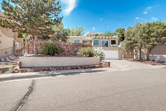 pueblo-style home with driveway, a garage, and stucco siding