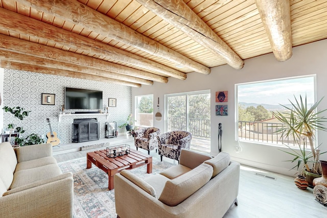 living area with a glass covered fireplace, wood ceiling, visible vents, and wood finished floors