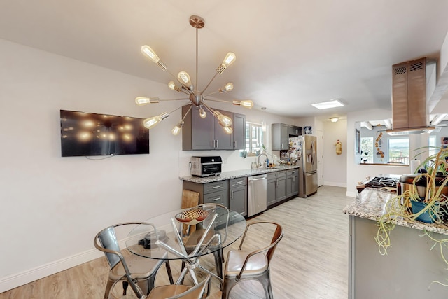 kitchen featuring light wood-style flooring, a sink, appliances with stainless steel finishes, gray cabinets, and island exhaust hood