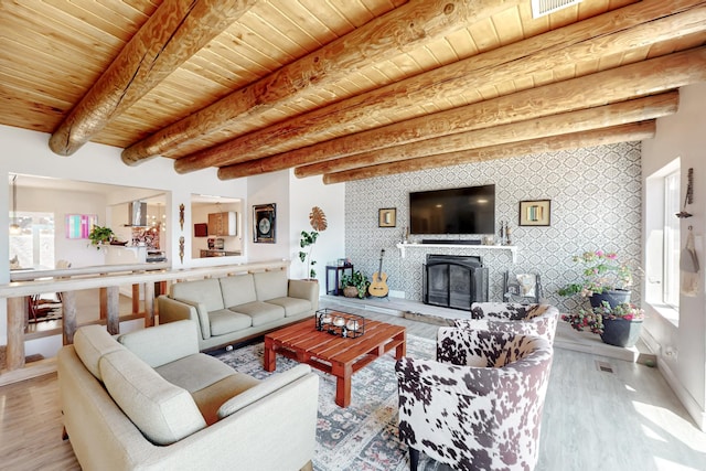 living area with an accent wall, a fireplace, wood ceiling, baseboards, and beam ceiling