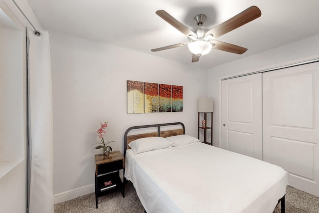 carpeted bedroom with a ceiling fan, a closet, and baseboards