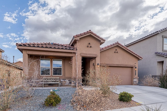 mediterranean / spanish-style house featuring a garage, concrete driveway, stone siding, and stucco siding