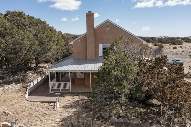 back of property with stucco siding, fence, a chimney, and a patio area