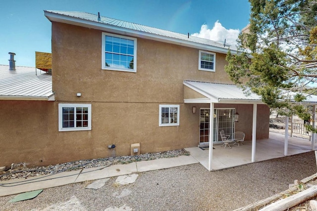 rear view of house featuring a patio, stucco siding, and metal roof