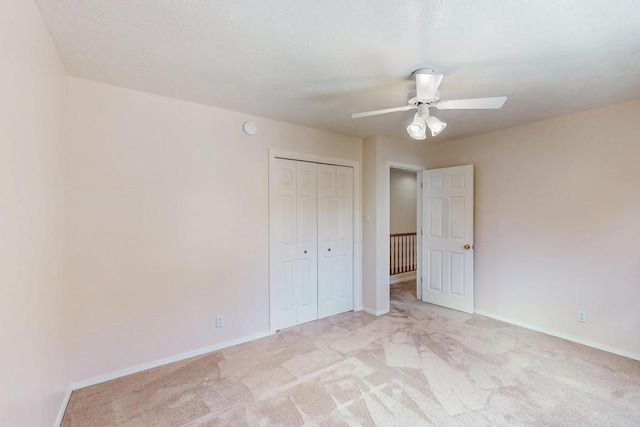 unfurnished bedroom with baseboards, a closet, and light carpet