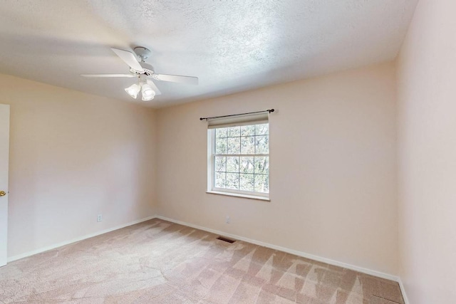 unfurnished room featuring visible vents, a ceiling fan, a textured ceiling, baseboards, and light colored carpet