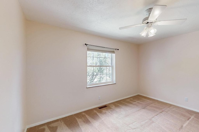 spare room featuring visible vents, light colored carpet, a textured ceiling, and baseboards