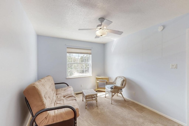 living area featuring baseboards, a textured ceiling, a ceiling fan, and carpet