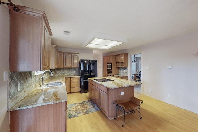 kitchen with visible vents, a sink, decorative backsplash, black appliances, and light wood-type flooring