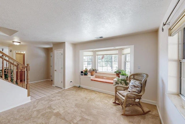 living area with stairs, light colored carpet, visible vents, and baseboards