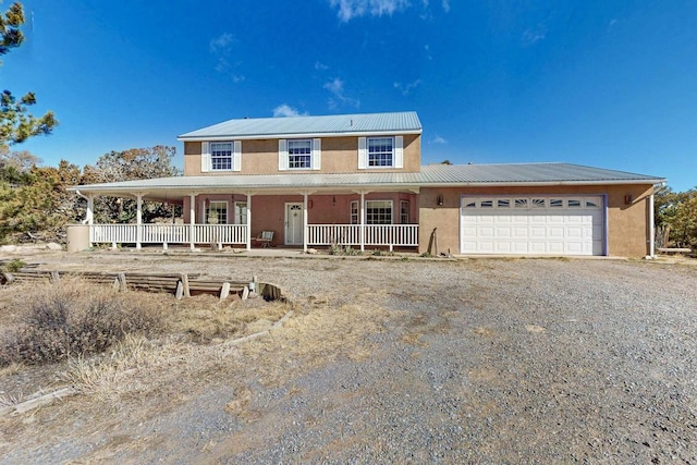 farmhouse with stucco siding, dirt driveway, covered porch, an attached garage, and metal roof