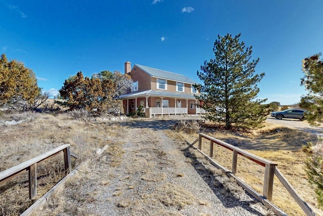 view of front of property with a porch, a chimney, and metal roof