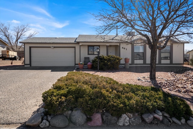 ranch-style house with gravel driveway, roof with shingles, and an attached garage