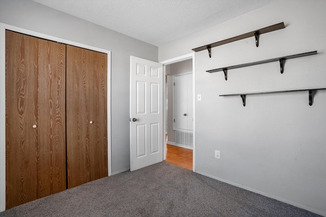 unfurnished bedroom featuring carpet floors, a closet, visible vents, and a textured ceiling