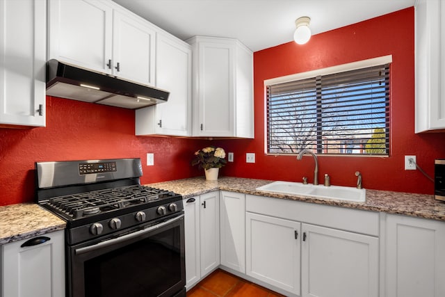 kitchen with white cabinets, a textured wall, under cabinet range hood, a sink, and gas stove