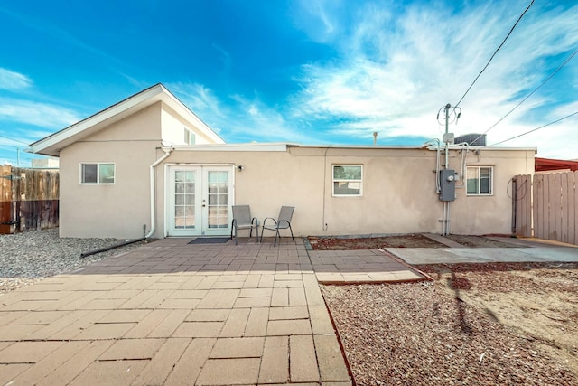 rear view of property with stucco siding, fence, a patio, and french doors