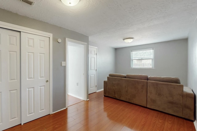 living room with a textured ceiling, wood finished floors, and baseboards