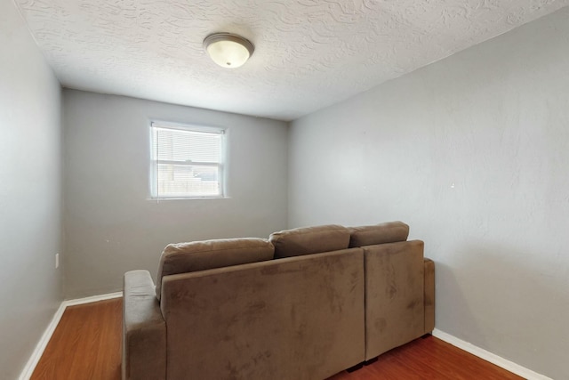 living area with a textured ceiling, wood finished floors, and baseboards