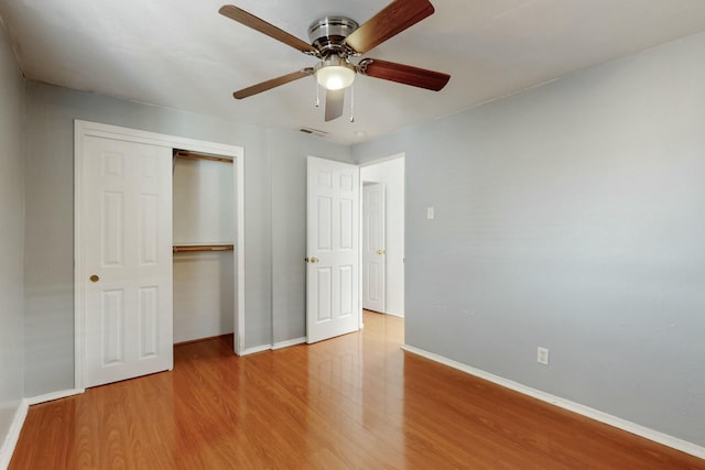 unfurnished bedroom featuring a closet, visible vents, ceiling fan, wood finished floors, and baseboards