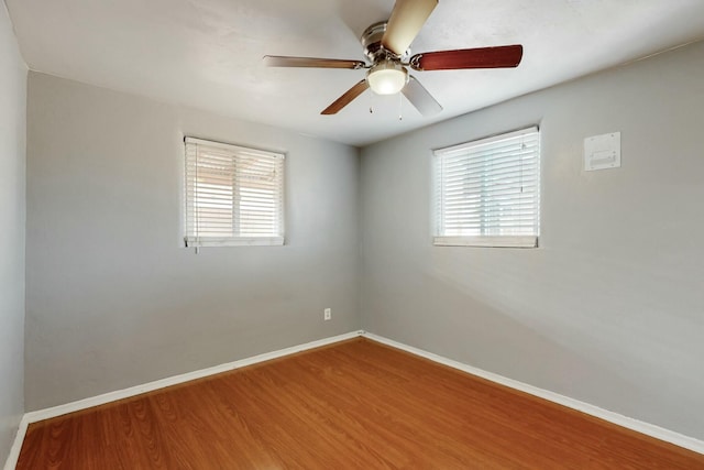 spare room featuring a healthy amount of sunlight, wood finished floors, and baseboards