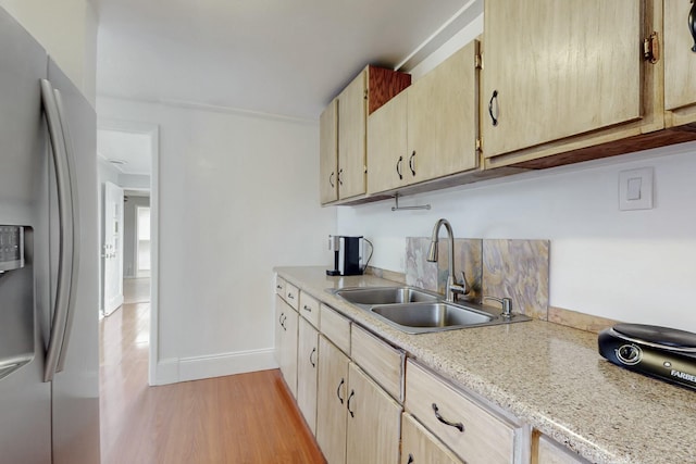 kitchen with light countertops, a sink, stainless steel refrigerator with ice dispenser, and light brown cabinetry