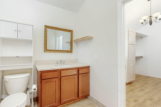 bathroom with toilet, a chandelier, wood finished floors, and vanity