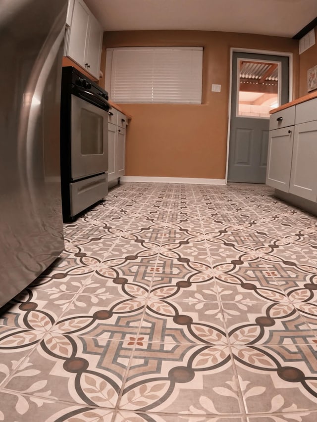 kitchen featuring double wall oven, baseboards, and freestanding refrigerator