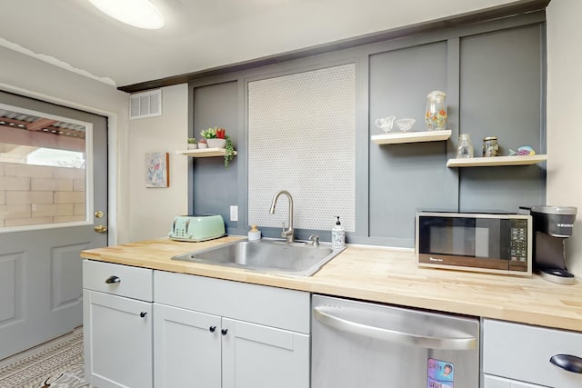 kitchen with a sink, visible vents, wood counters, stainless steel dishwasher, and open shelves