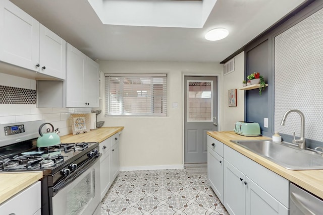 kitchen featuring stainless steel appliances, visible vents, backsplash, a sink, and wood counters