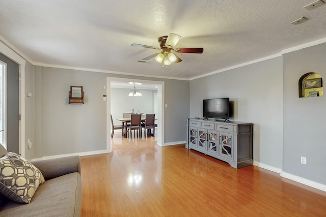 living area with a textured ceiling, baseboards, wood finished floors, and crown molding